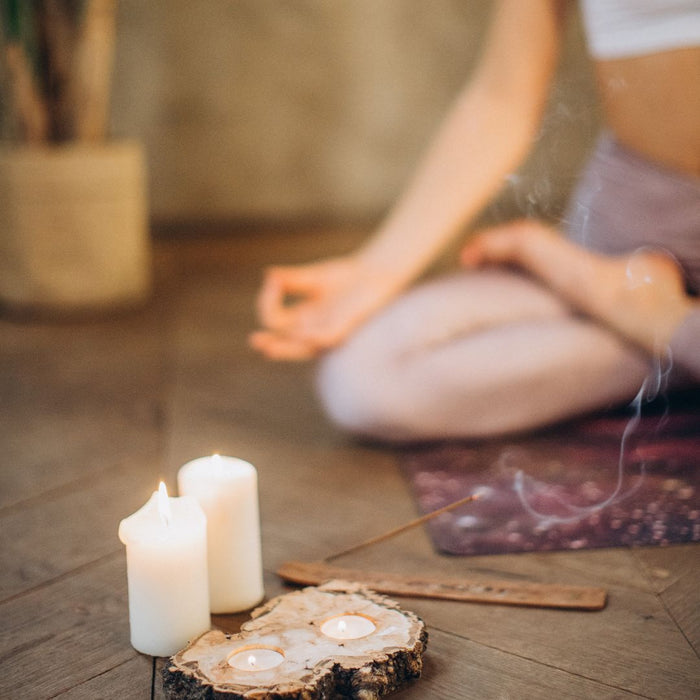 Person meditating with candles and incense on a wooden floor